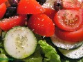 close up of a salad with tomatoes, cucumbers, lettuce and dried herbs