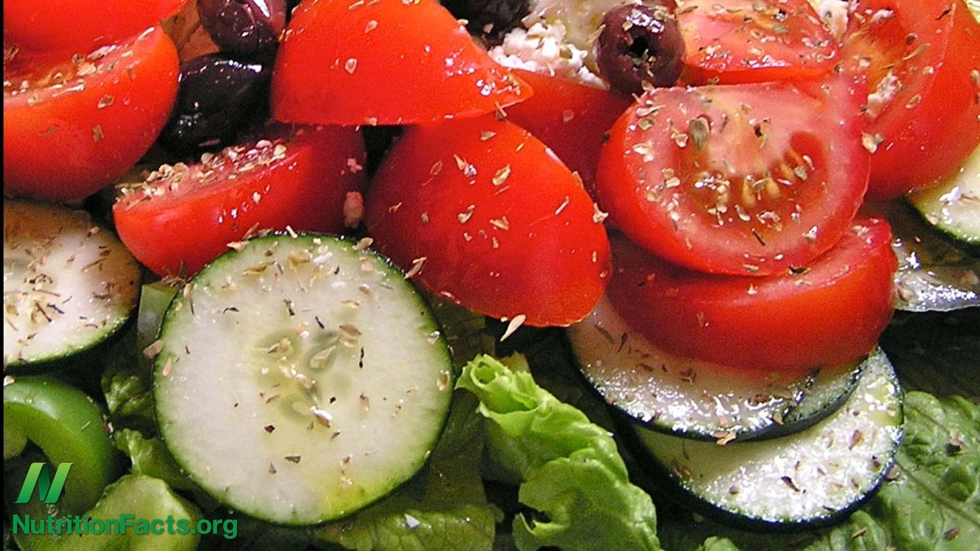 close up of a salad with tomatoes, cucumbers, lettuce and dried herbs