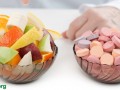a bowl of cut-up fruit alongside a bowl of various pills