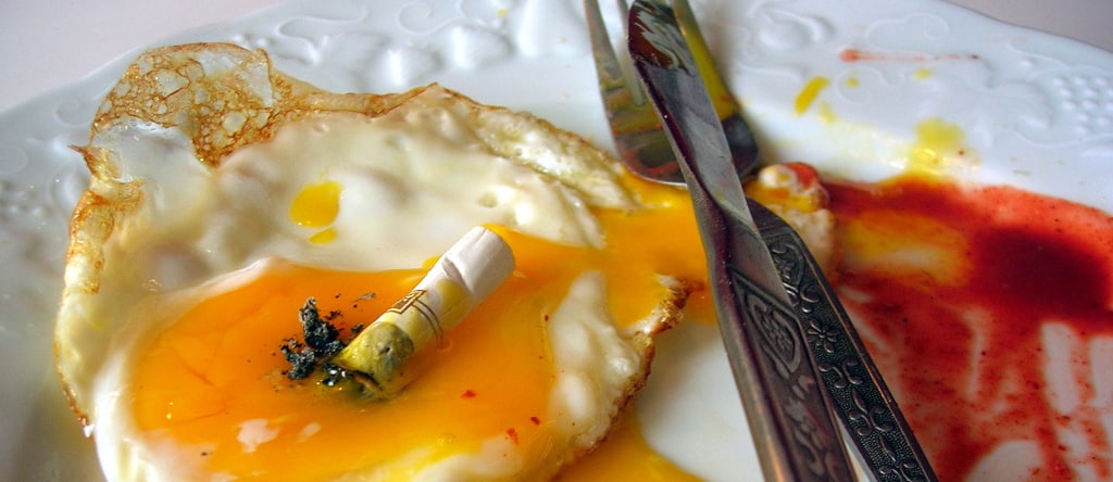 plate of a fried egg with a cigarette on top of it