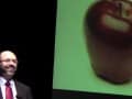 Dr. Greger in front of a large screen with an apple on it
