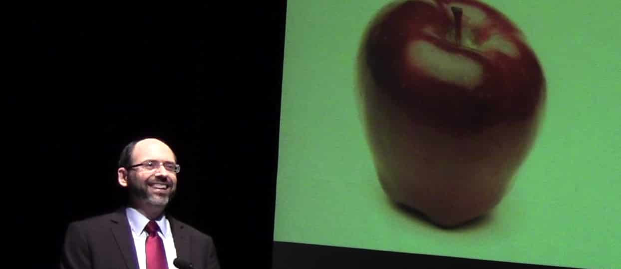 Dr. Greger in front of a large screen with an apple on it