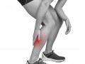 black and white image of a person grabbing their calf that is shaded red