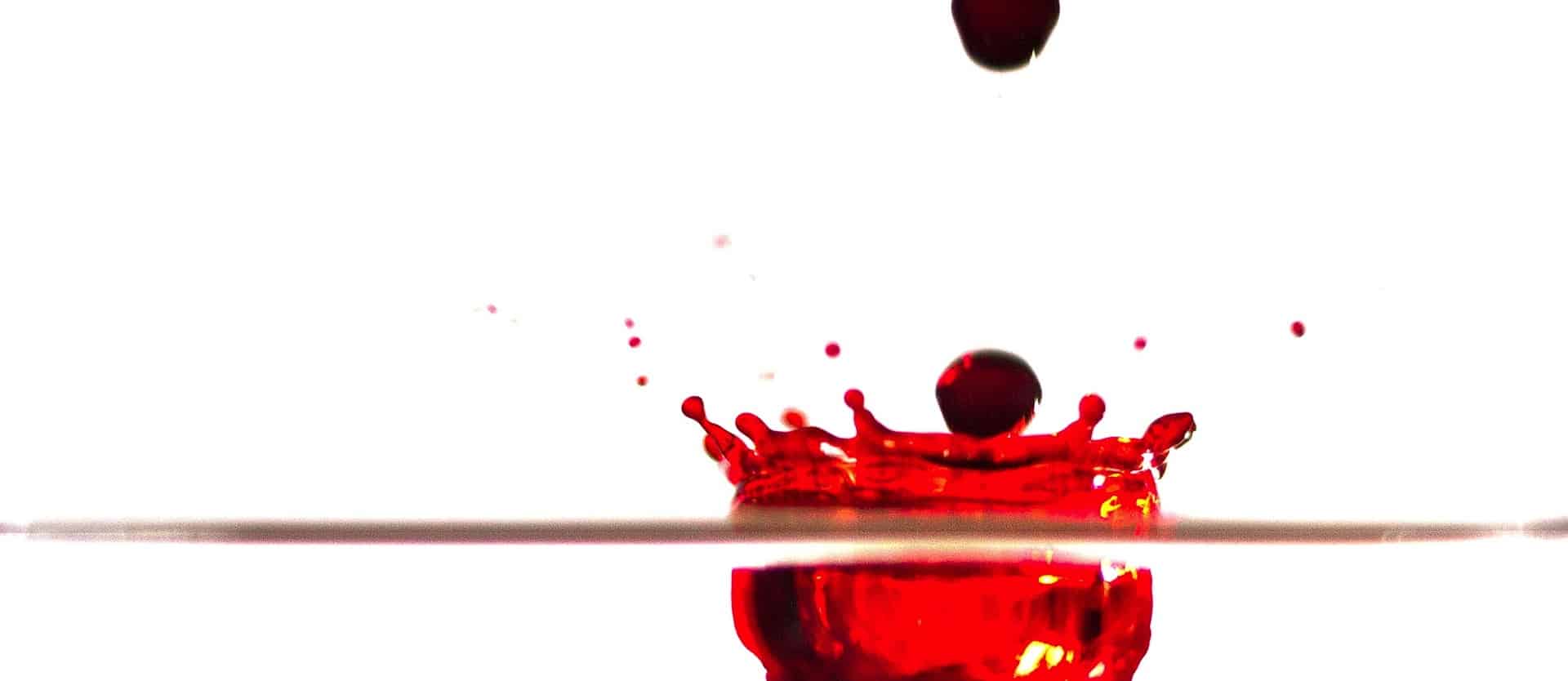 drops of red food dye splashing onto a surface