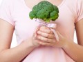 woman holding a piece of broccoli with a pink ribbon tied around it