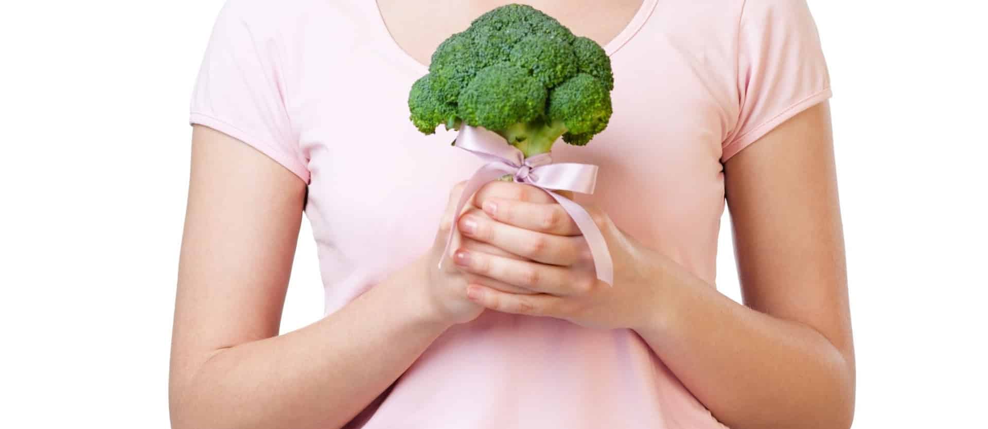 woman in a pink shirt holding a piece of broccoli