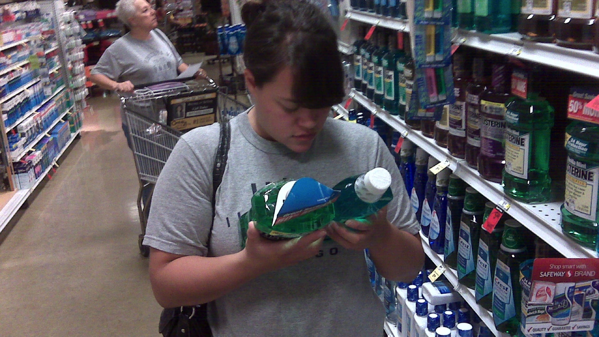 person in a shopping aisle comparing bottles of mouthwash