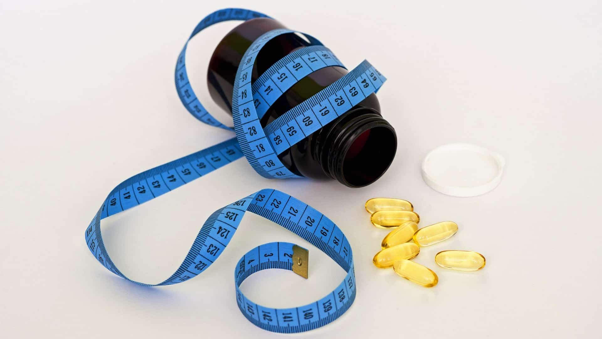 bottle of supplements with a tape measure wrapped around it