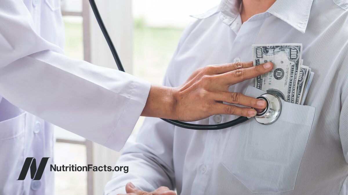 doctor with stethoscope on patient with money in pocket
