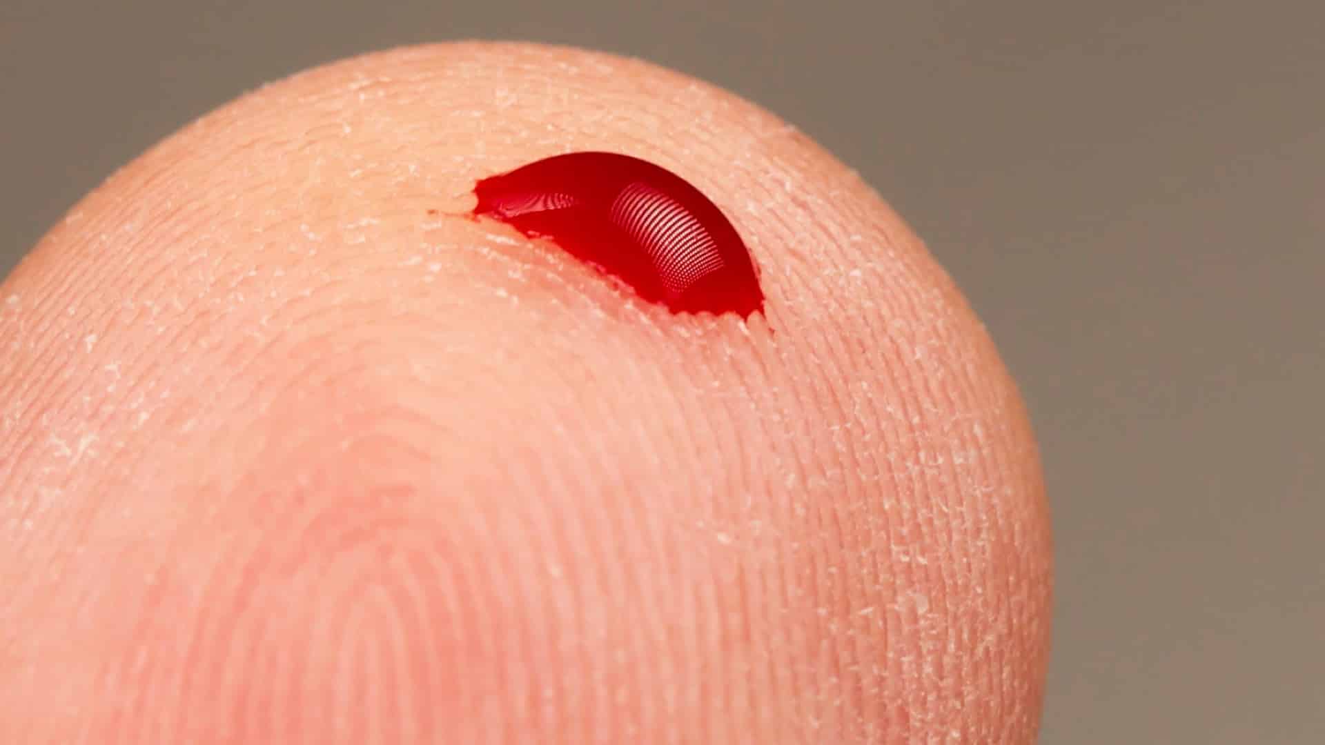 close-up of a finger tip with a drop of blood on it