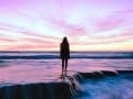 silhouette of a person standing in water at sunset