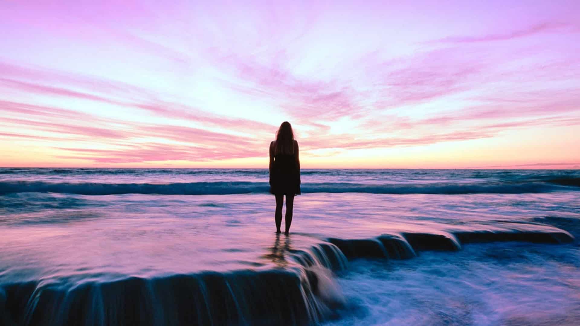 silhouette of a person standing in water at sunset