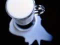glass mug of milk with milk spilled around it