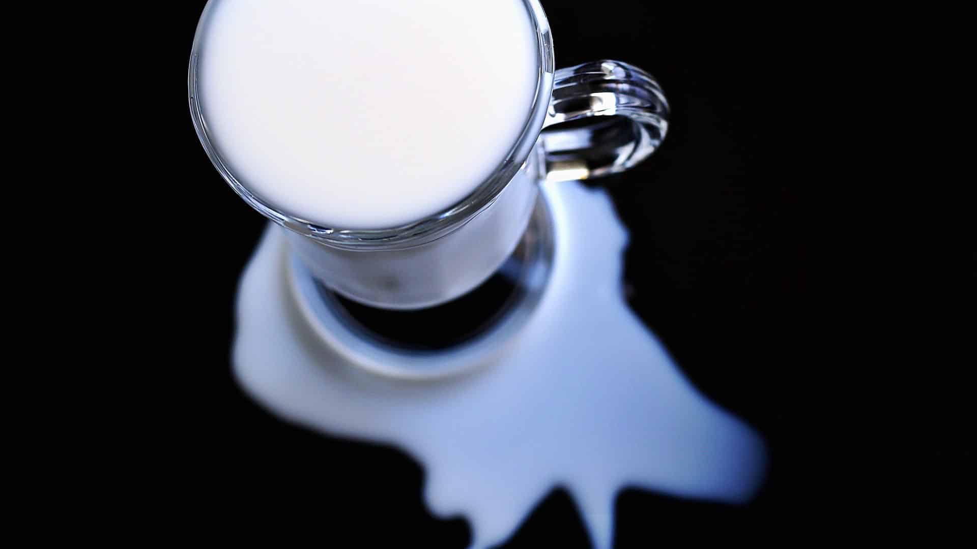 glass mug of milk with milk spilled around it