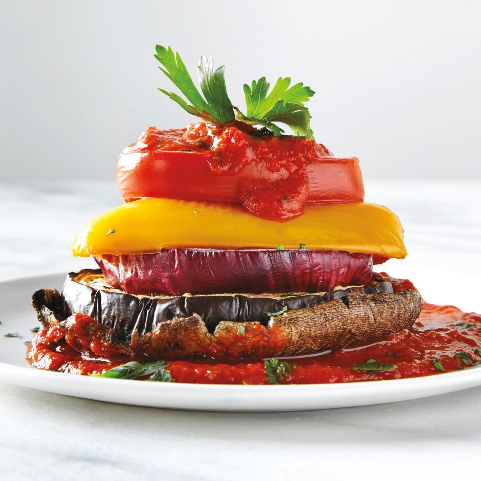 layers of various vegetables with a sauce on a plate