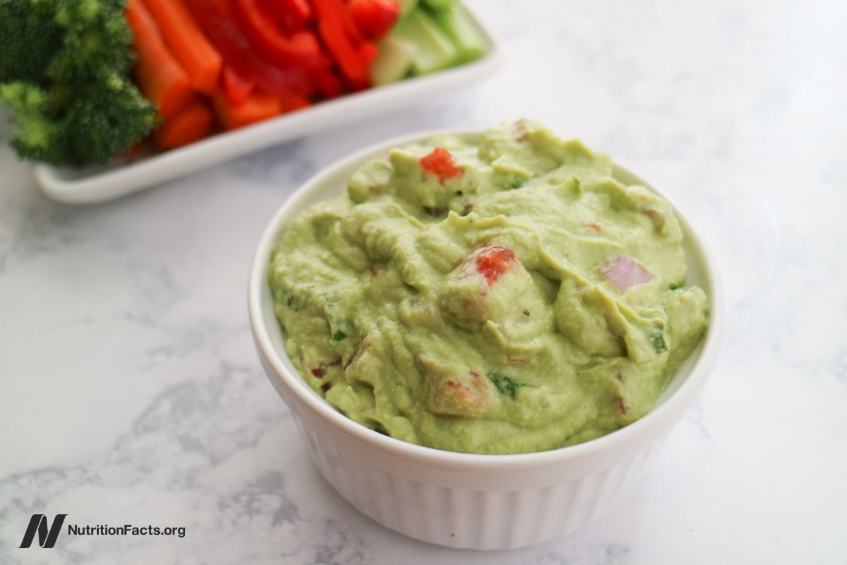 ramekin of edamame guacamole with sliced vegetables in the background