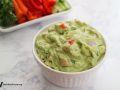 ramekin of edamame guacamole with sliced vegetables in the background