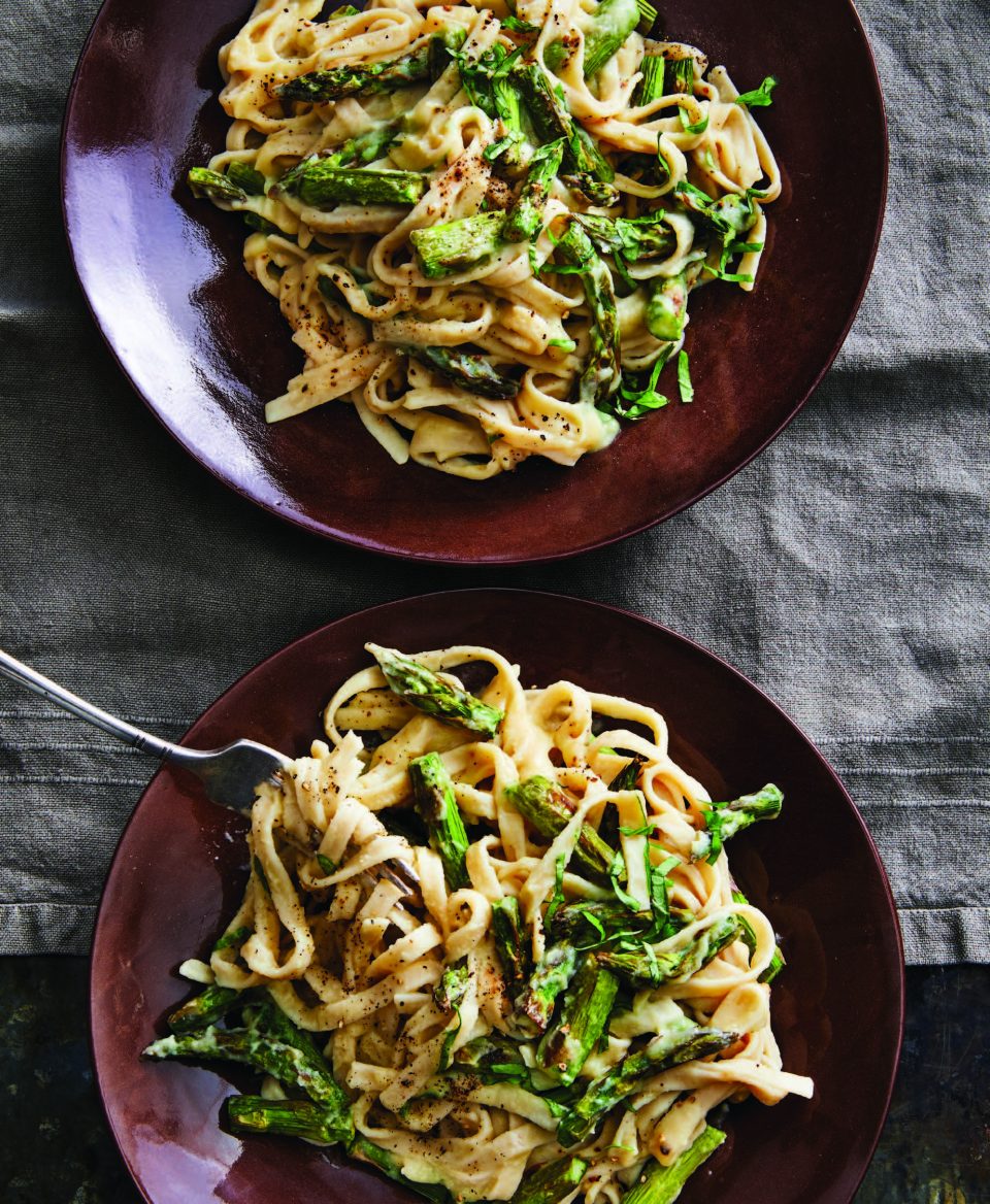 two bowls of cauliflower alfredo pasta and asparagus