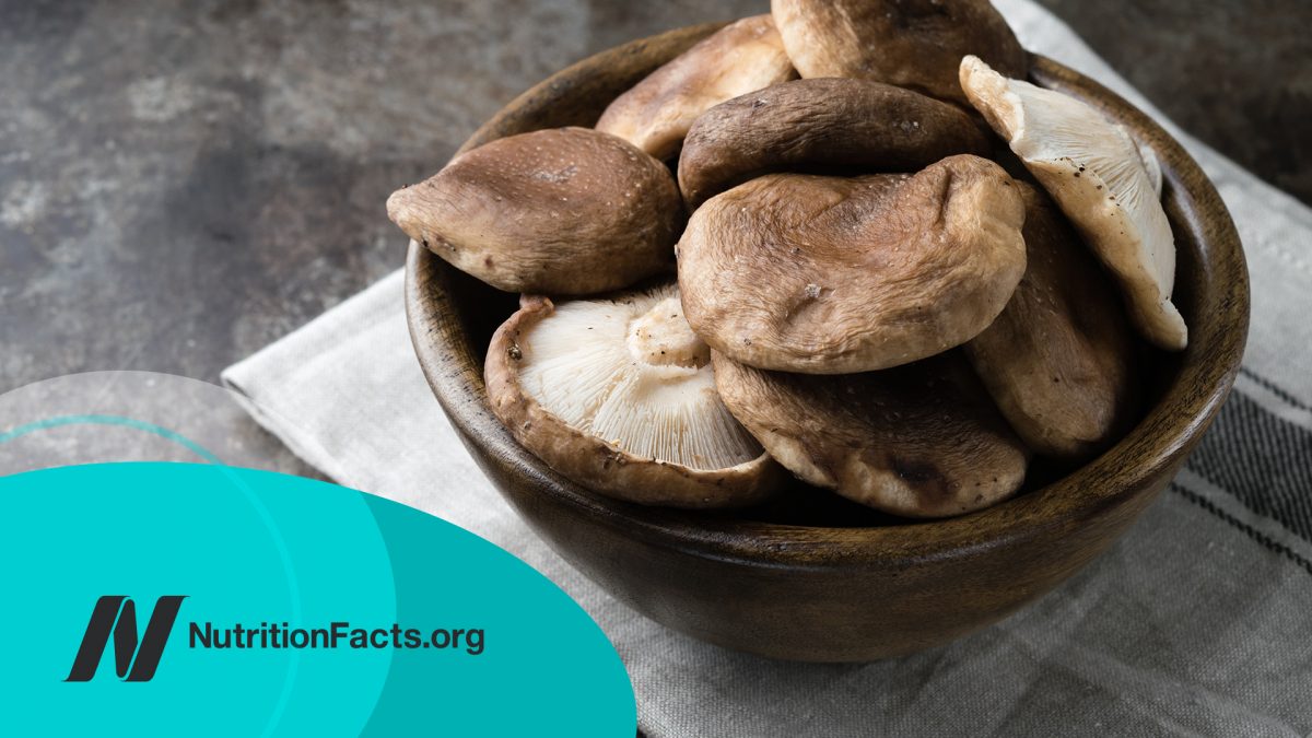 Wooden bowl with raw mushrooms on a dark background