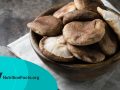 Wooden bowl with raw mushrooms on a dark background
