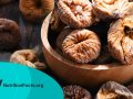 Composition with bowl of dried figs on wooden table