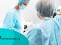 doctor in protective mask performing surgery while assistants help him
