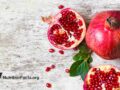 half pomegranate and ripe pomegranate fruit on white wooden rustic background
