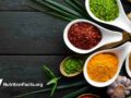 spice and herb collection in bowls and spoons on a black wooden background