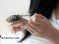 woman looking at her hairbrush with hair