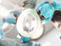 bottom view of three doctors leaning over the patient holding anesthetic inhaler