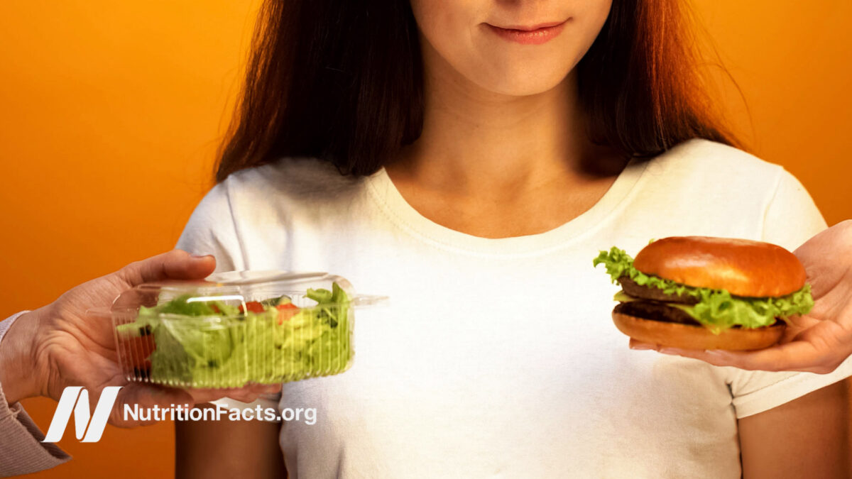 Woman choosing between salad and hamburger