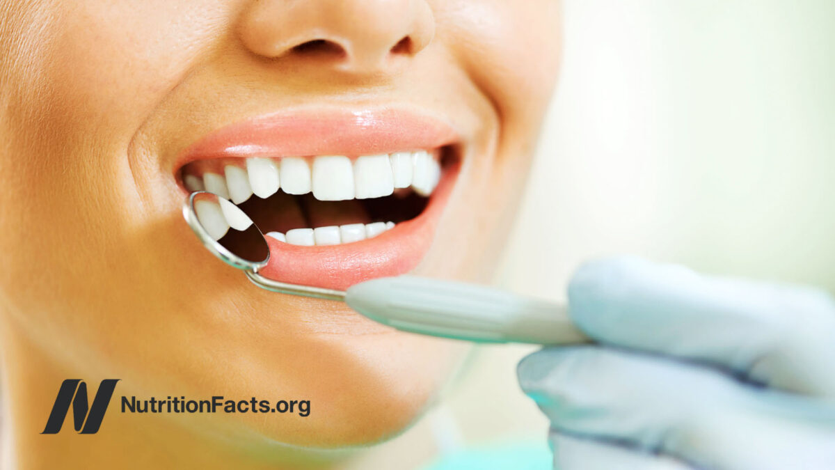 Gloved hand holding dental mirror to inspect teeth
