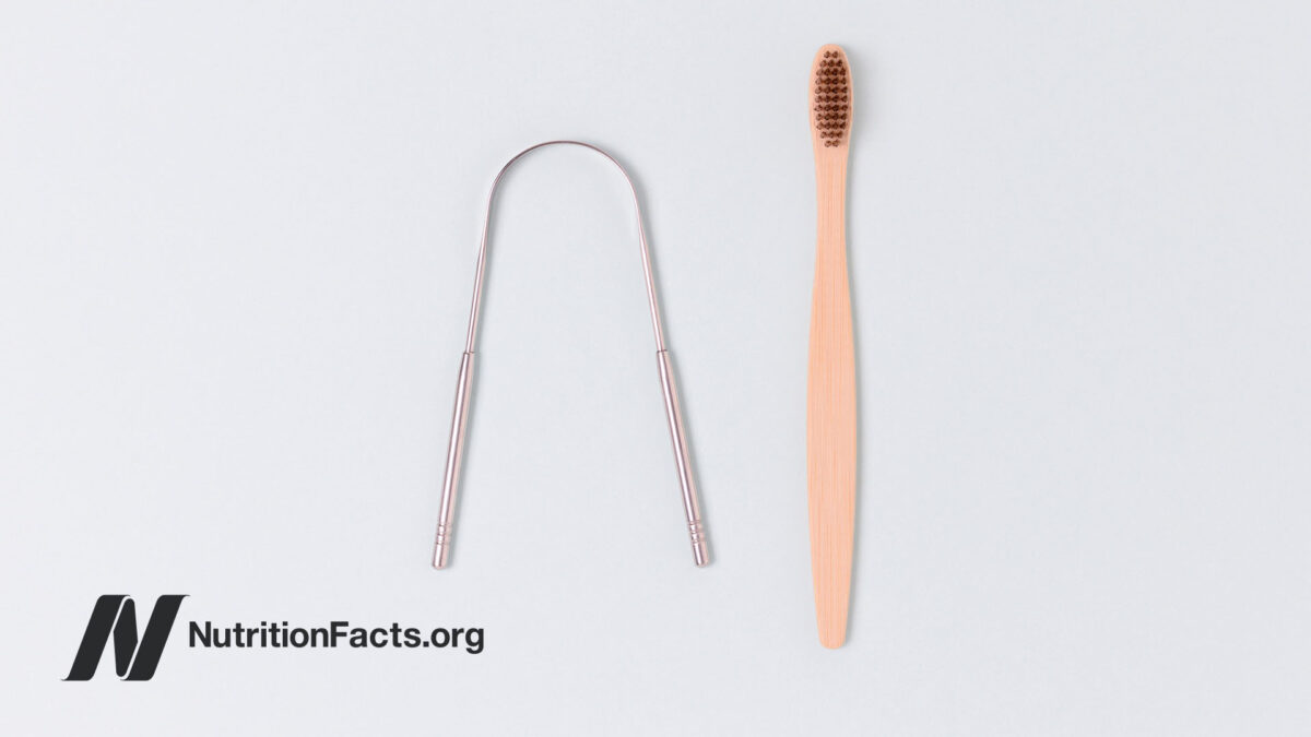 Tongue scraper and pink toothbrush on white surface