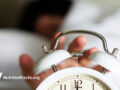 Hand reaching for the stopper on an alarm clock