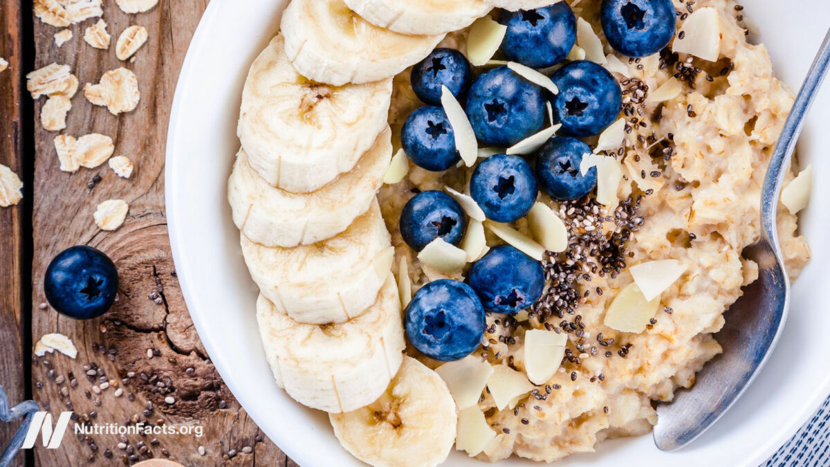 Oatmeal in a bowl on a wood surface with banana and blueberries