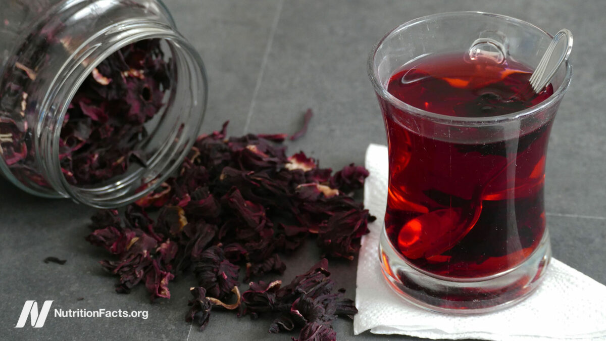 Glass of steeping hibiscus tea and loose leaf laying around