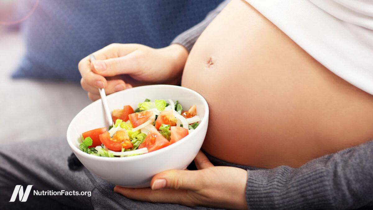 Pregnant person holding a white bowl of whole food