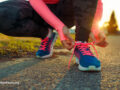 Person kneeling down to tie sneakers