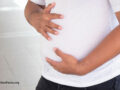 Person in a white shirt holding their stomach