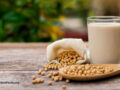Closeup soy bean in sack and white cup of soy milk with green nature background