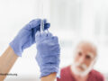 Close up of female medic preparing to make injection. Old man on blurred background
