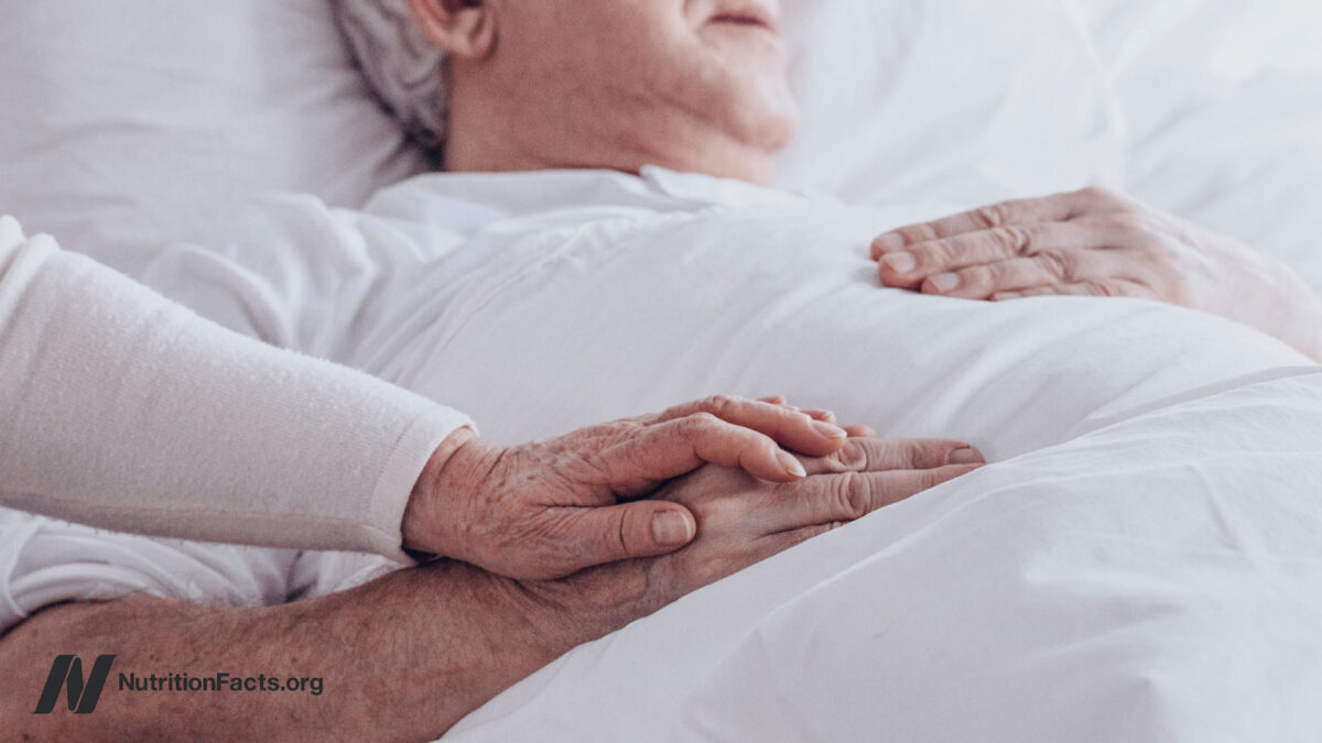 Loving person touching hands and supporting sick partner on the bed