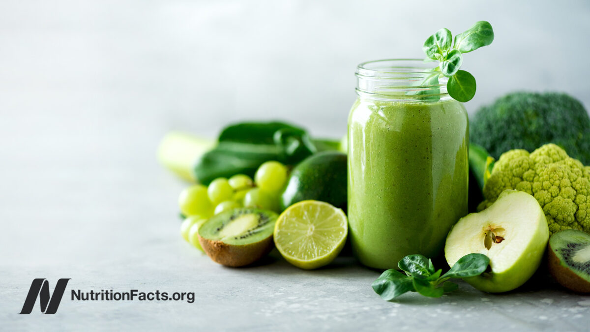 a green juice surrounded by green fruits and veggies