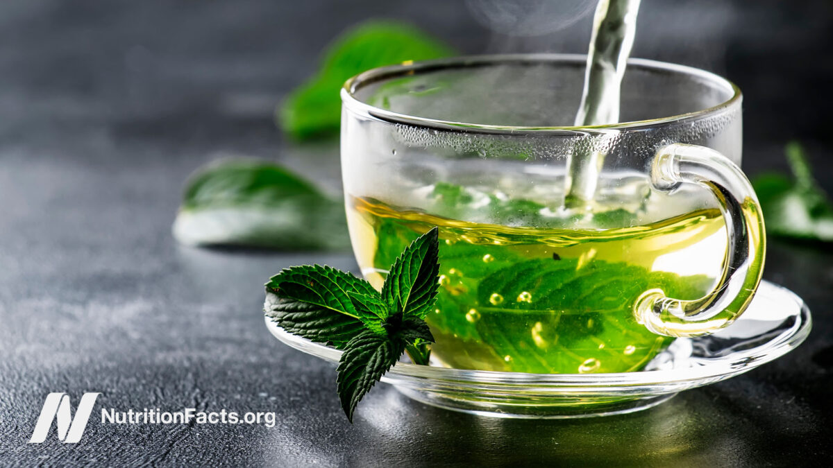 Green tea in a glass mug on a table outside