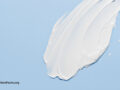 White cosmetic cream lotion moisturizer strokes on pastel blue