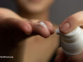 Closeup of a young woman applying prescription retinoid to her face