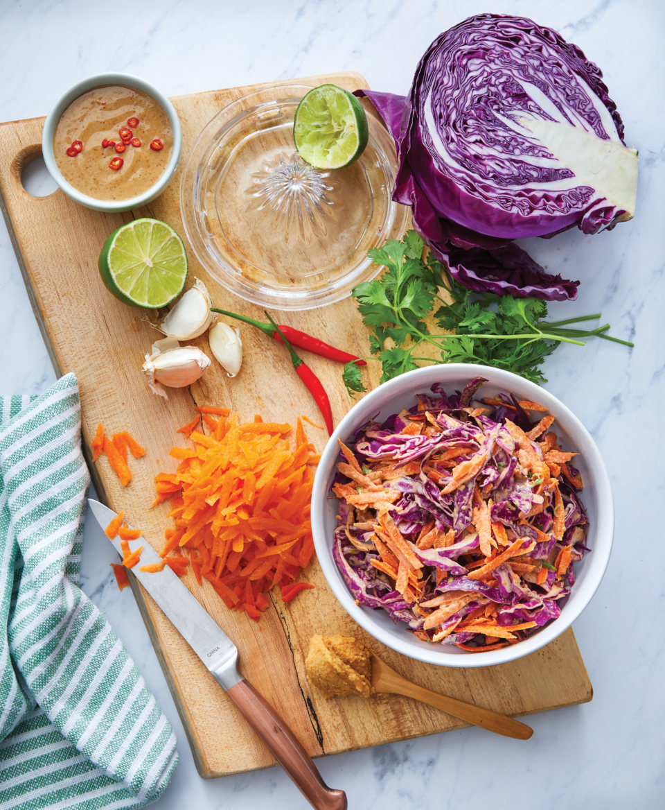 bowl of purple cabbage slaw with ingredients laid out around it