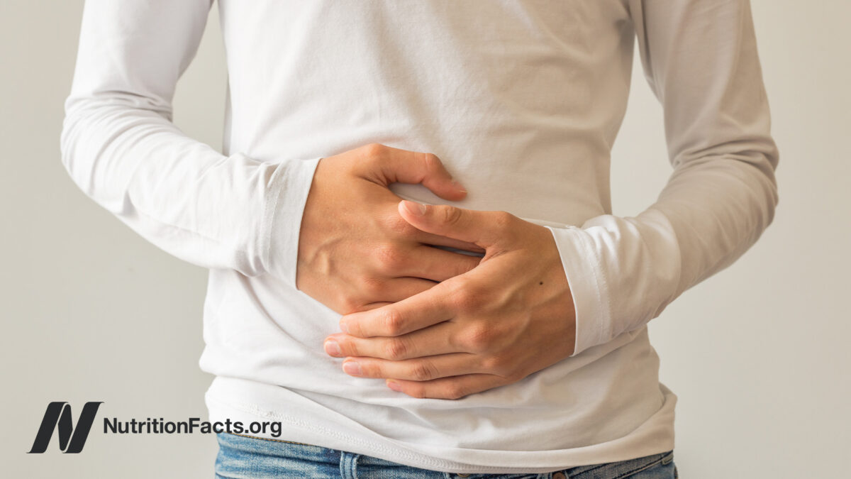 Person with a long sleeved white shirt and jeans holding their hands over their stomach
