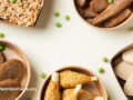 Paper containers holding plant based meat alternatives with several peas on white background