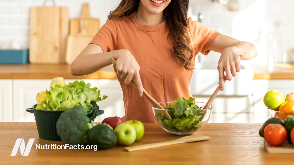 A woman happily preparing a fresh salad